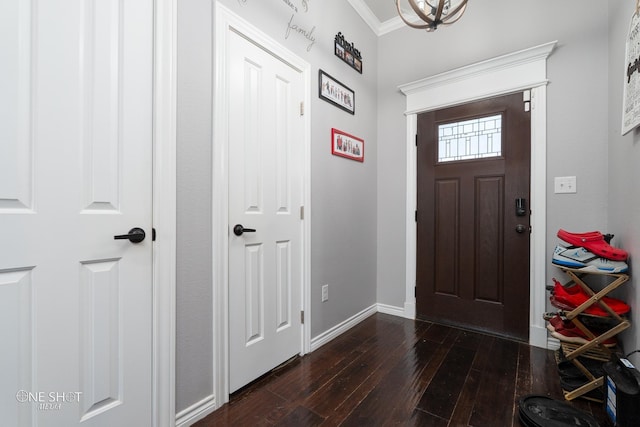 foyer with dark wood finished floors, crown molding, and baseboards