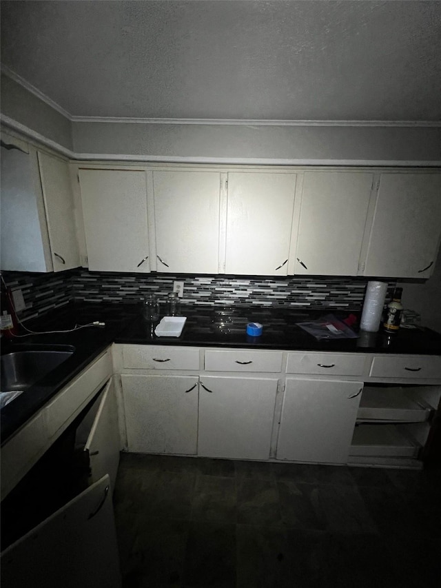 kitchen featuring backsplash, dark countertops, white cabinets, and a sink