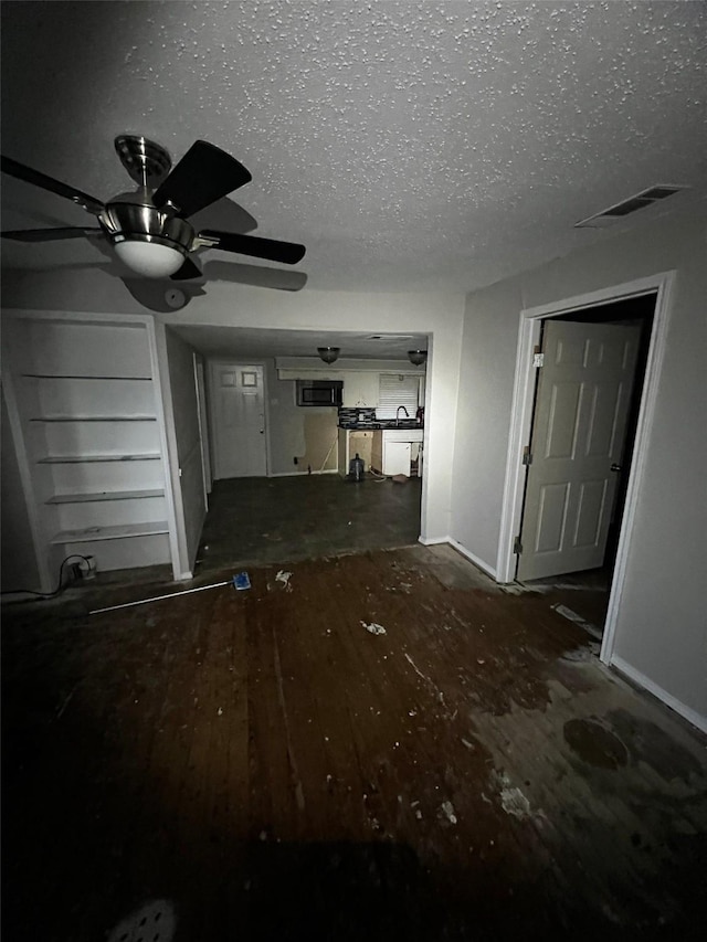 unfurnished living room with a sink, visible vents, a textured ceiling, and wood finished floors