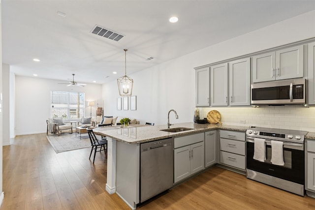 kitchen featuring gray cabinetry, stainless steel appliances, a peninsula, and a sink