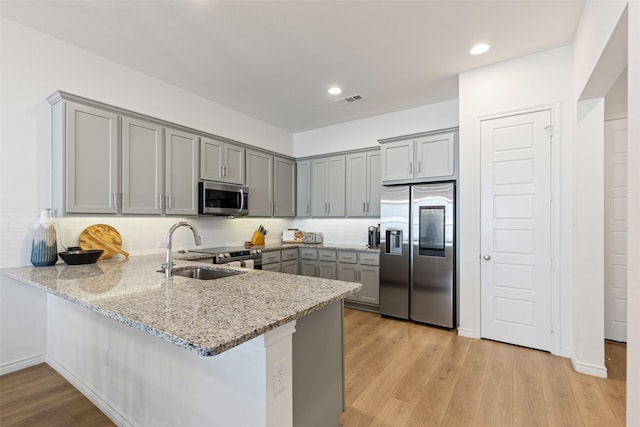 kitchen featuring a peninsula, visible vents, gray cabinets, and stainless steel appliances