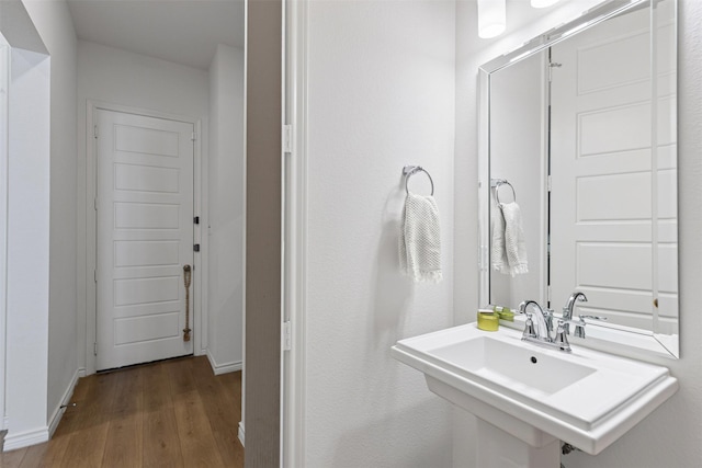 bathroom featuring wood finished floors, baseboards, and a sink