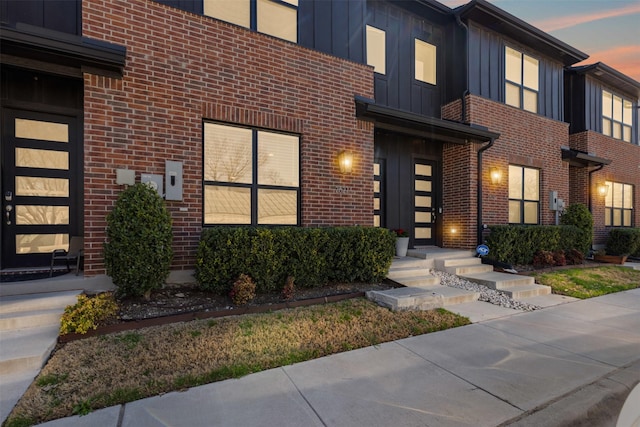 doorway to property featuring brick siding and board and batten siding