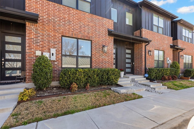 view of exterior entry featuring brick siding and board and batten siding