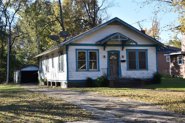 bungalow-style home with driveway, a front lawn, and an outdoor structure