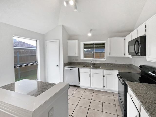 kitchen featuring light tile patterned floors, black appliances, dark stone counters, and a sink