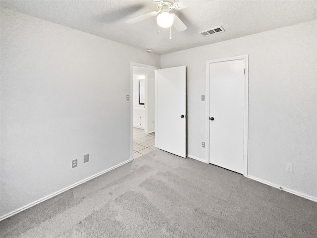 unfurnished bedroom with a ceiling fan, visible vents, carpet floors, and baseboards