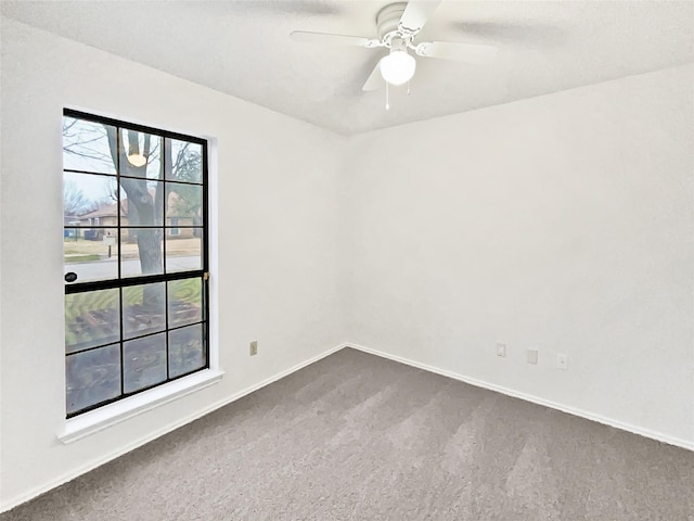 unfurnished room featuring dark carpet, baseboards, and a ceiling fan