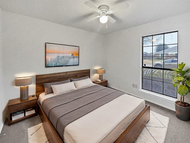 bedroom featuring a ceiling fan, carpet floors, and a textured ceiling