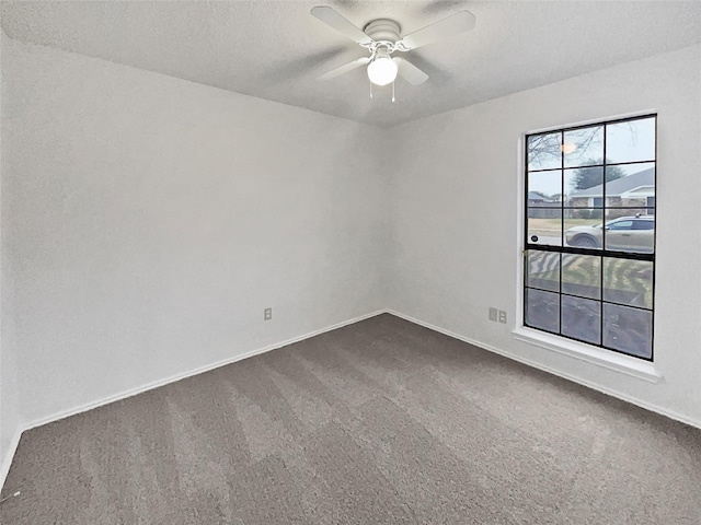 empty room featuring baseboards, a ceiling fan, dark colored carpet, and a textured ceiling