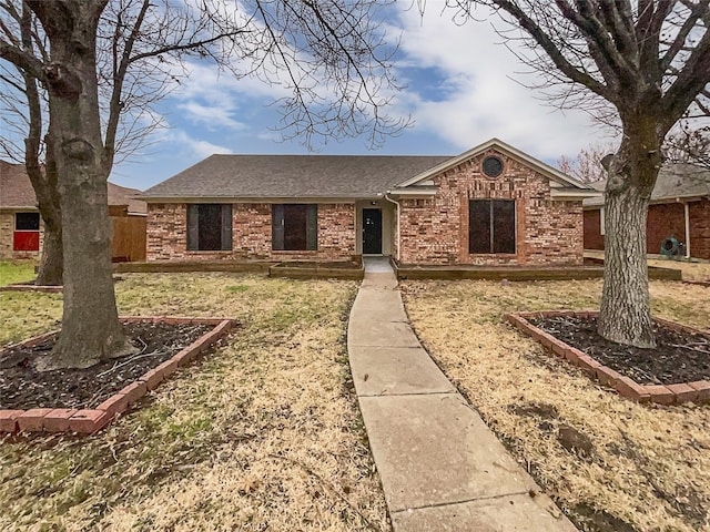 ranch-style house featuring brick siding and a shingled roof