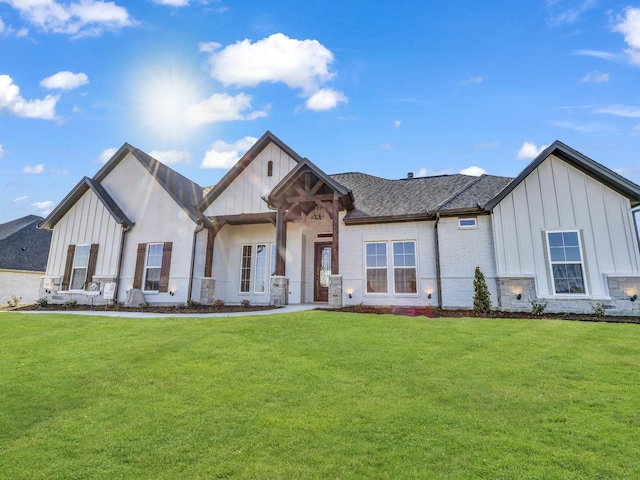 modern inspired farmhouse with brick siding, board and batten siding, a front yard, and a shingled roof