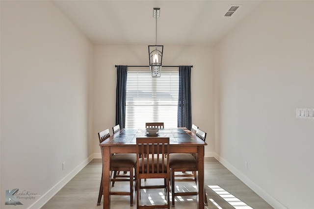 dining area with a notable chandelier, light wood-style floors, visible vents, and baseboards