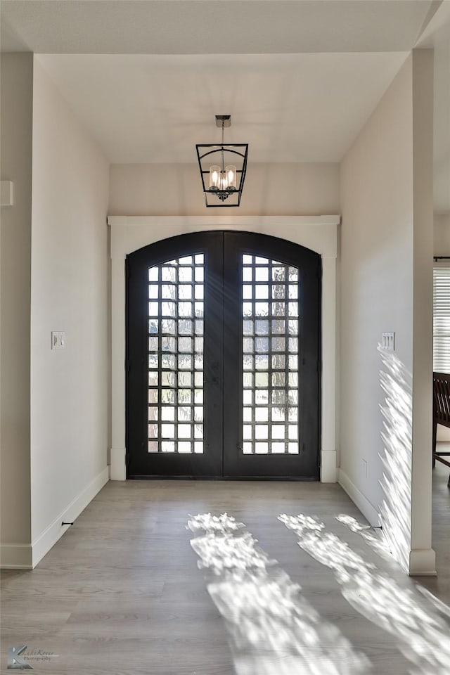 entryway with french doors, baseboards, a notable chandelier, and wood finished floors