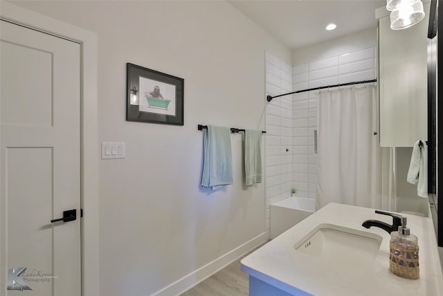 full bath with a shower with curtain, wood finished floors, baseboards, recessed lighting, and a sink