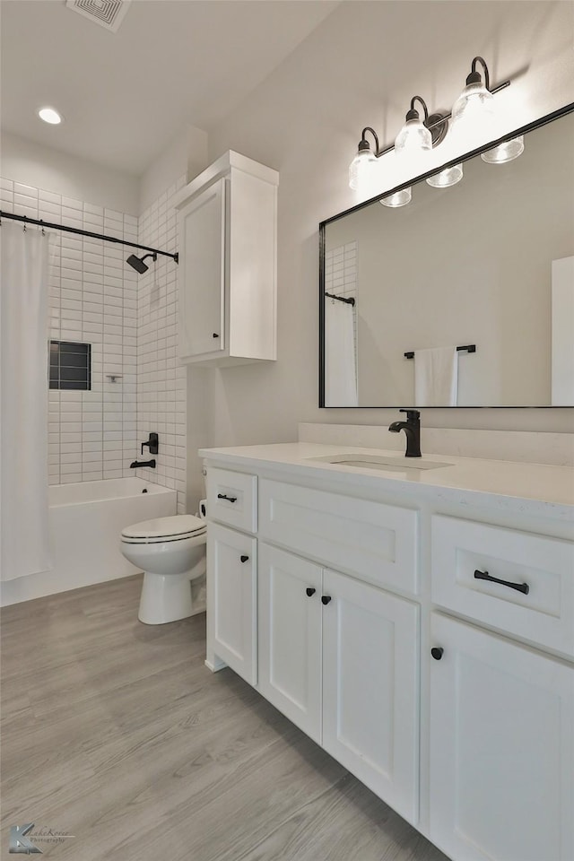 full bathroom with visible vents, toilet, shower / tub combo with curtain, wood finished floors, and vanity