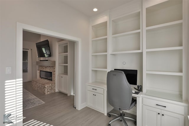 office with recessed lighting, a fireplace, light wood-style floors, and built in shelves