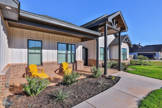 doorway to property with brick siding, board and batten siding, and covered porch