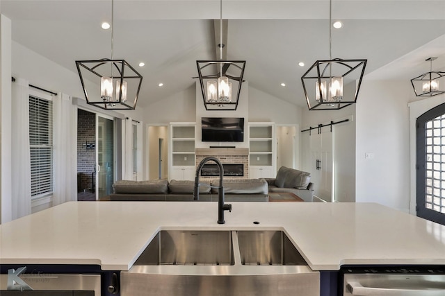 kitchen featuring open floor plan, dishwasher, a barn door, a fireplace, and an inviting chandelier