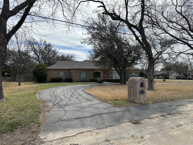 ranch-style house with aphalt driveway, fence, and a front yard