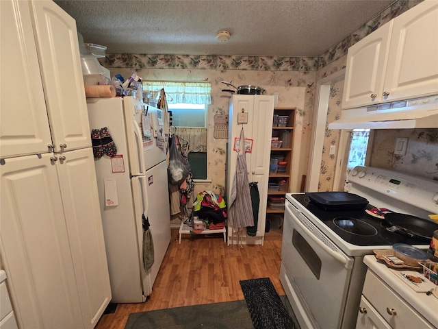 kitchen with wallpapered walls, under cabinet range hood, light wood-type flooring, white appliances, and a textured ceiling