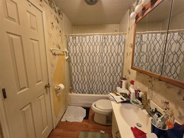 bathroom with wallpapered walls, toilet, vanity, wood finished floors, and a textured ceiling