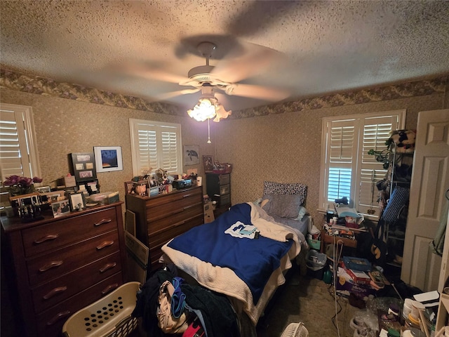 bedroom with wallpapered walls, a textured ceiling, and ceiling fan