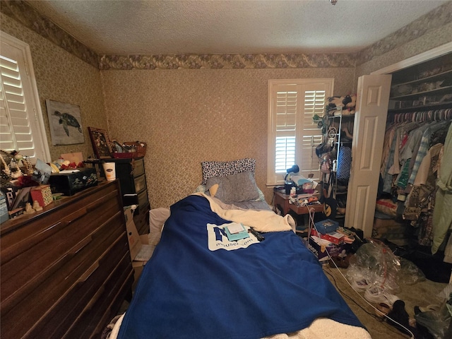 bedroom featuring wallpapered walls and a textured ceiling