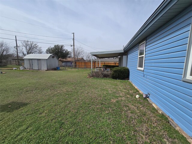 view of yard featuring an outbuilding, a storage shed, and fence