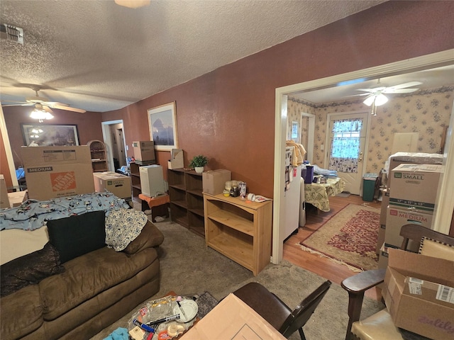 living room featuring visible vents, a textured ceiling, wood finished floors, and a ceiling fan