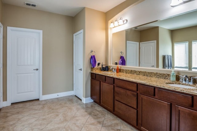 bathroom with a sink, visible vents, baseboards, and double vanity