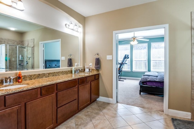 full bath with a shower stall, baseboards, double vanity, tile patterned floors, and a sink