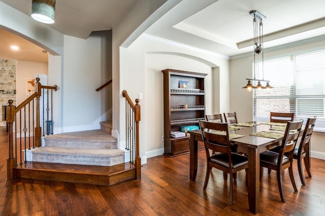 dining room with a tray ceiling, baseboards, dark wood finished floors, and crown molding