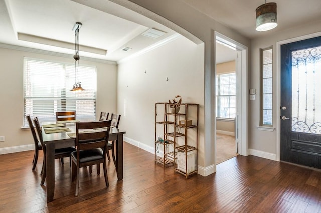 dining space featuring a tray ceiling, baseboards, ornamental molding, and dark wood-style flooring