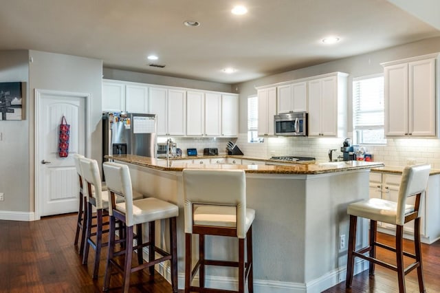 kitchen with stainless steel microwave, visible vents, dark wood-style flooring, and white cabinetry