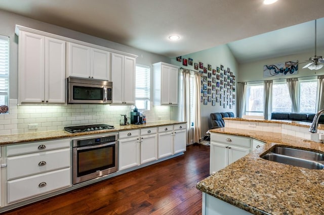 kitchen with dark wood-type flooring, a sink, backsplash, white cabinetry, and stainless steel appliances