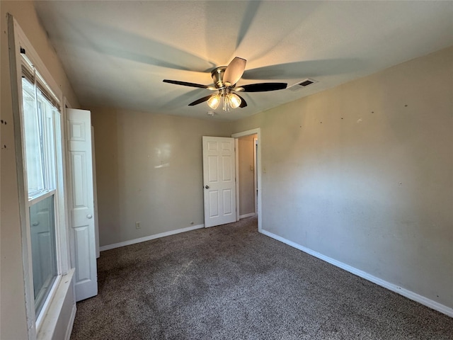 carpeted spare room with visible vents, baseboards, and ceiling fan