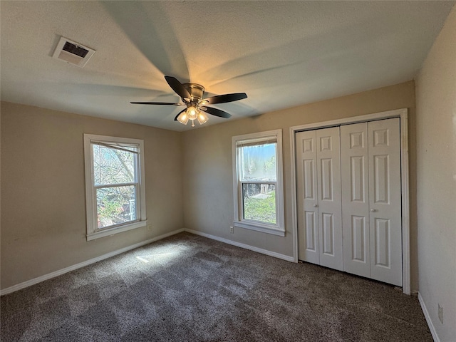 unfurnished bedroom with multiple windows, carpet, visible vents, and baseboards