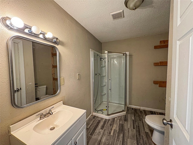 full bathroom with toilet, wood finished floors, a stall shower, a textured wall, and a textured ceiling