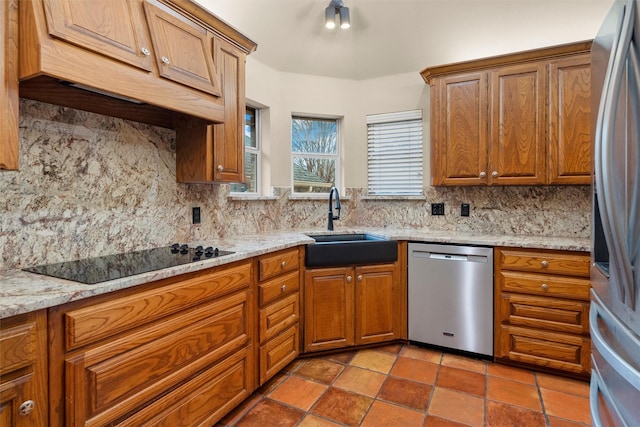 kitchen with brown cabinetry, backsplash, appliances with stainless steel finishes, and a sink