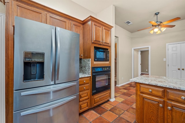 kitchen featuring brown cabinetry, visible vents, black appliances, and light stone countertops