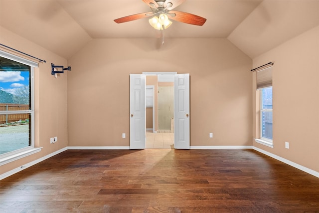 unfurnished room featuring vaulted ceiling, wood finished floors, and baseboards