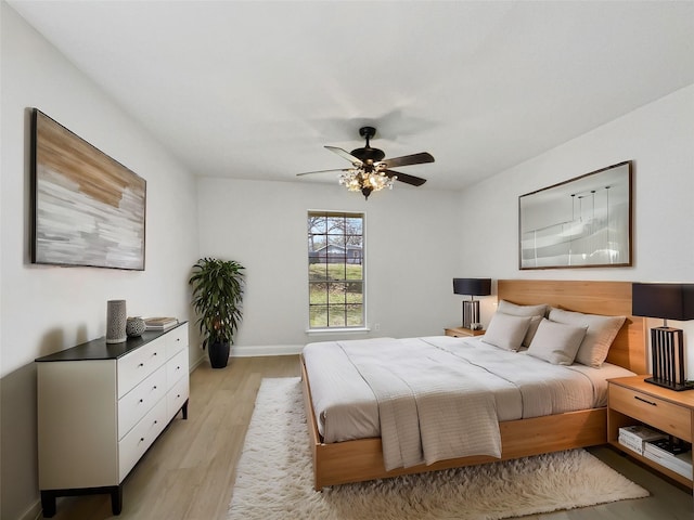 bedroom featuring a ceiling fan, baseboards, and light wood finished floors