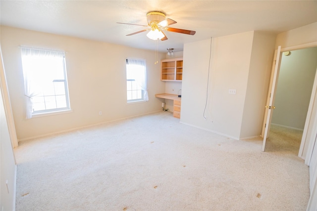 unfurnished bedroom featuring baseboards, carpet, a ceiling fan, and built in study area