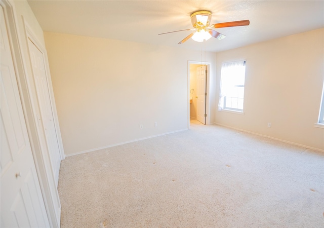 unfurnished bedroom with light carpet, connected bathroom, a ceiling fan, and baseboards