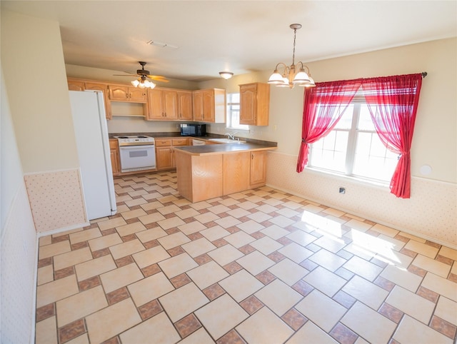 kitchen featuring light brown cabinetry, wainscoting, white appliances, and a peninsula