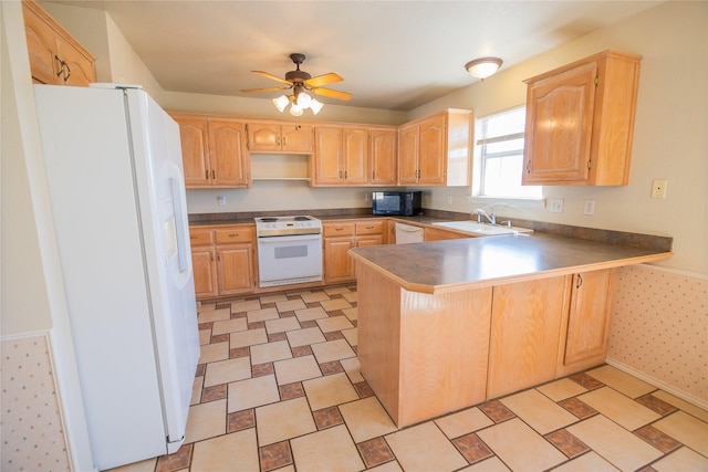 kitchen featuring light brown cabinetry, white appliances, a peninsula, and a sink