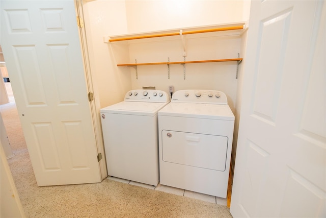 clothes washing area featuring washer and dryer, light tile patterned flooring, and laundry area