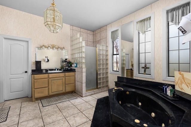 bathroom featuring tile patterned flooring, a jetted tub, vanity, and a tile shower