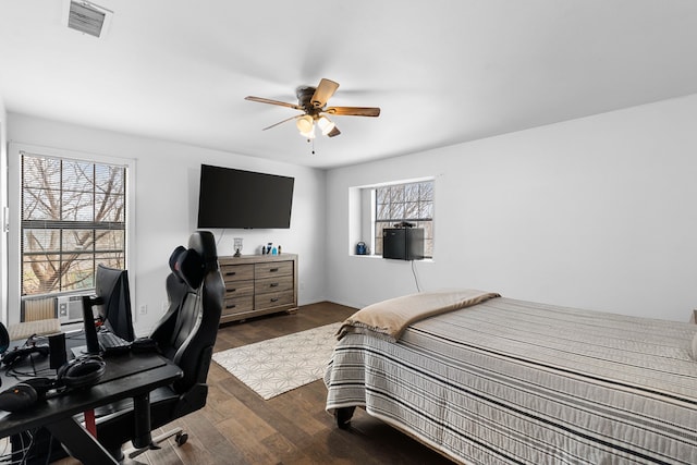 bedroom with a ceiling fan, dark wood-style floors, and visible vents